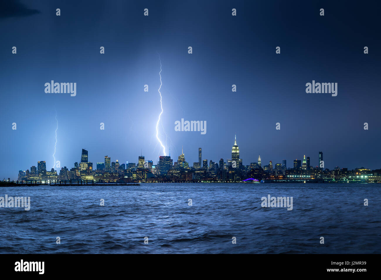 Blitze schlagen New York Wolkenkratzer in der Nacht. Stürmischer Himmel über Midtown West Manhattan vom Hudson River Stockfoto