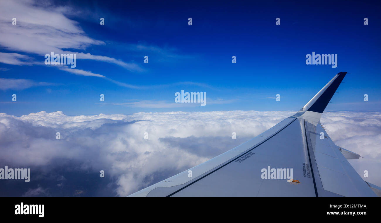 Flügel eines Flugzeugs über Wolken am blauen Himmelshintergrund Stockfoto