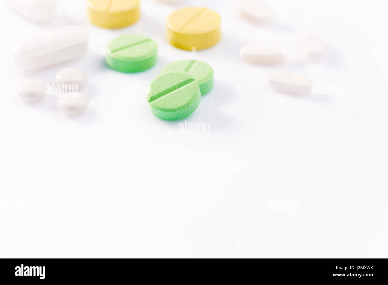 Medizin Pillen in verschiedenen Formen, Farben und Größen auf weißem Hintergrund mit selektiven Fokus auf die vordere grüne Pille Unschärfe Hintergrund, hart und niedrig ein Stockfoto