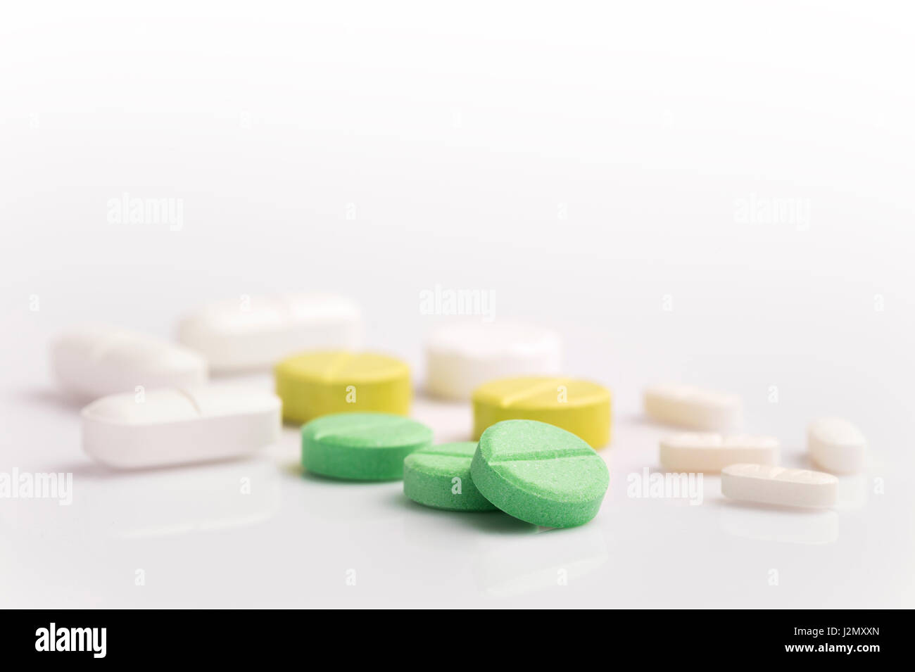 Medizin-Pillen in verschiedenen Formen, Farben und Größen auf weißem Hintergrund mit selektiven Fokus auf die vordere grüne Pille, Raum für Exemplar auf der Oberseite Stockfoto