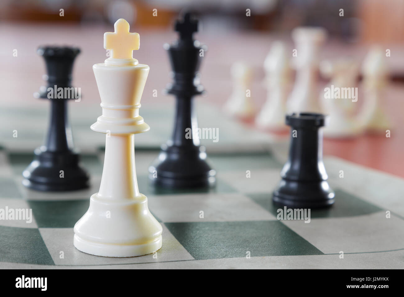Weiße Schachkönig allein inmitten der gegenüberliegenden Stücke, selektiven Fokus auf weißen Schachkönig Stück Stockfoto