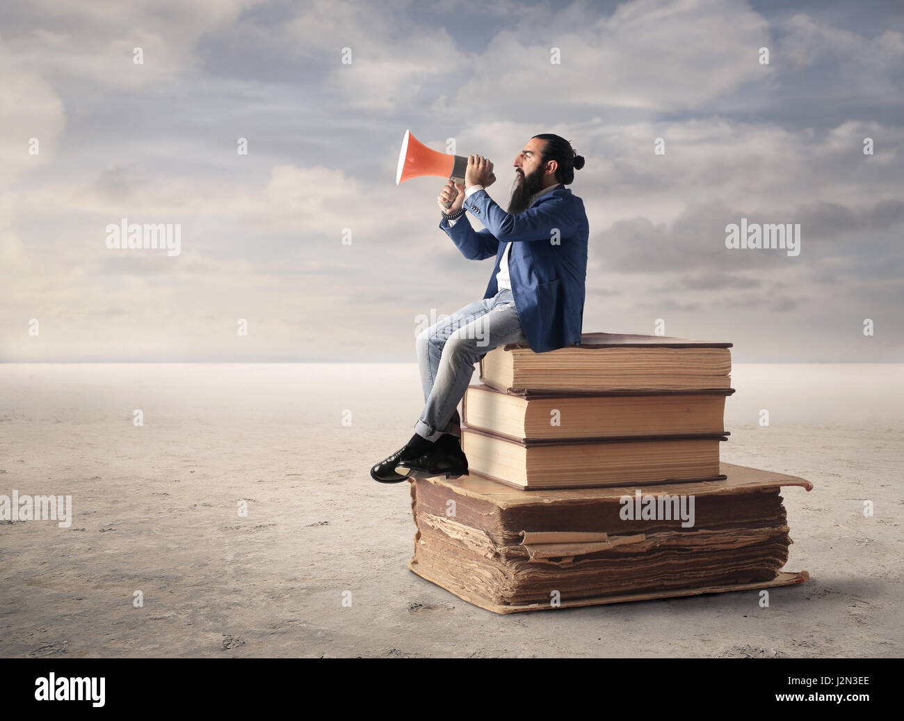 Geschäftsmann mit Megaphon auf große Bücher Stockfoto