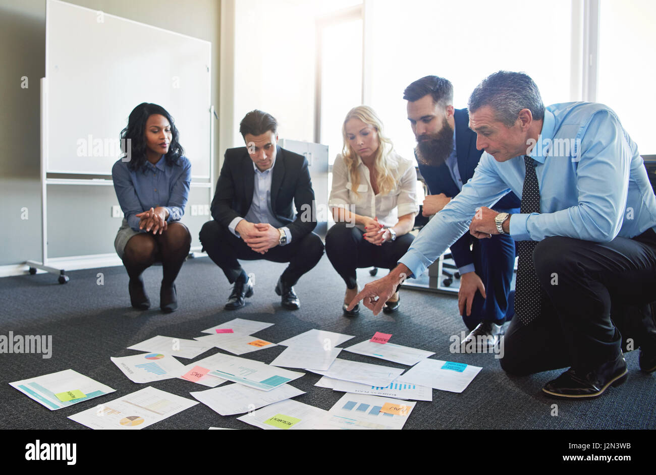 Business Team Brainstorming in Büro, geduckt auf verschiedene Ideen auf dem Boden zu suchen Stockfoto
