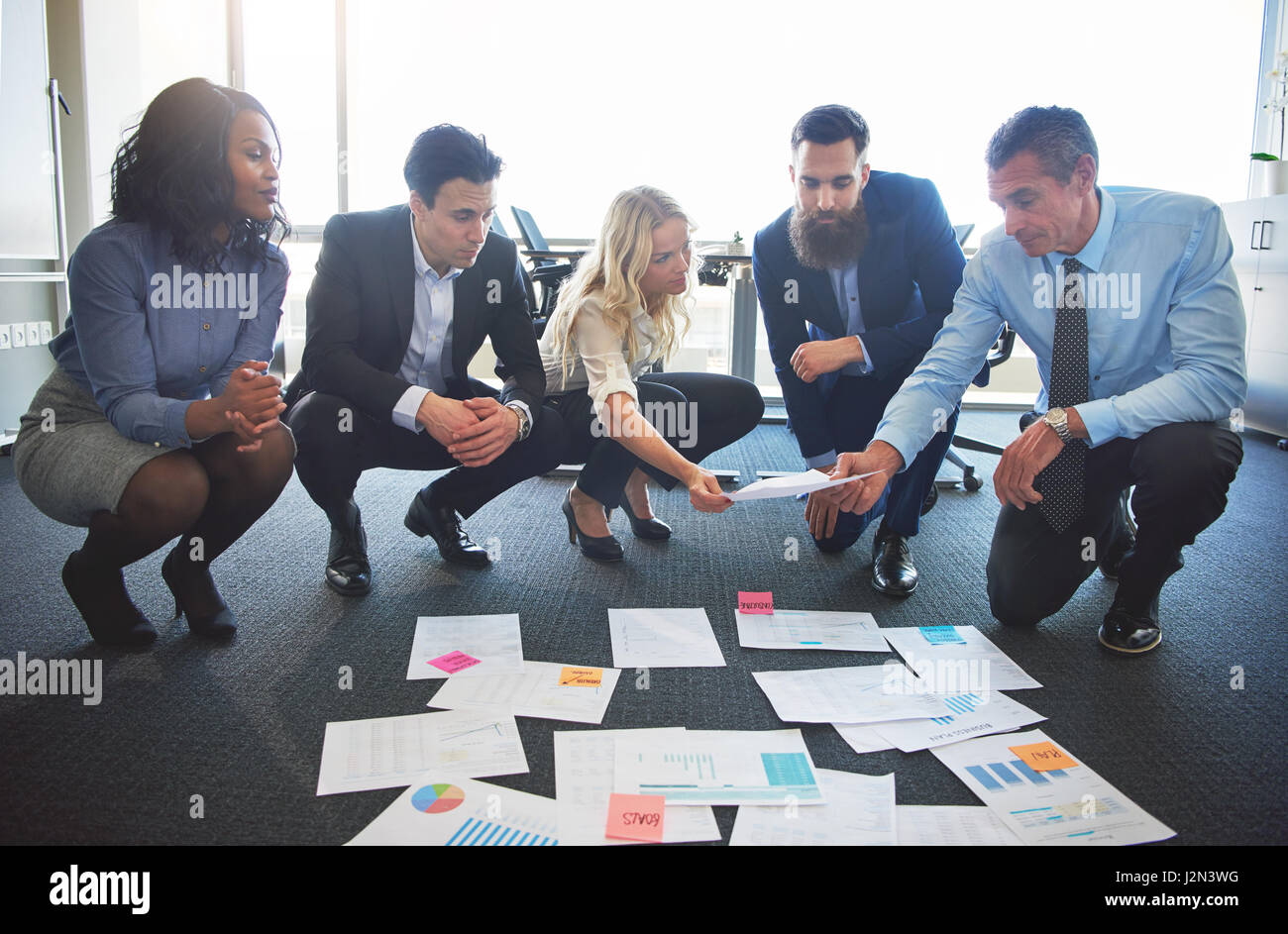 Business-Team Ideen im Büro, den Austausch von Dokumenten, während am Boden kauerte vergleichen Stockfoto