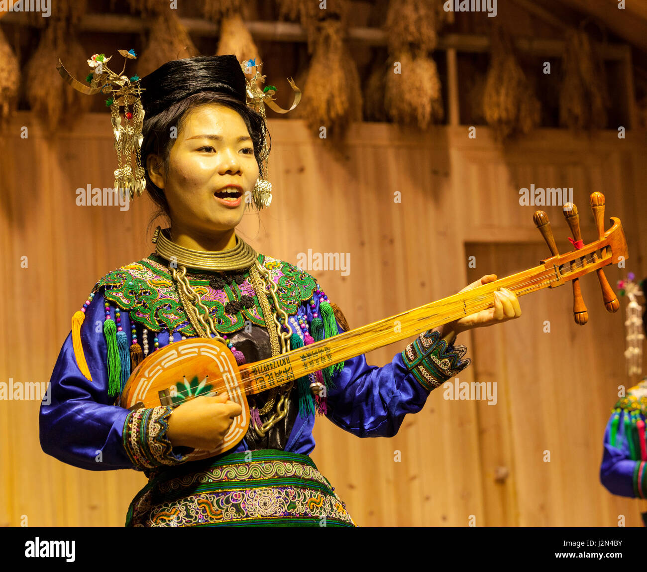 Zhaoxing, Guizhou, China.  Junge Frau von der Dong ethnische Minderheit spielt eine fünf-saitige laute (Pipa). Stockfoto