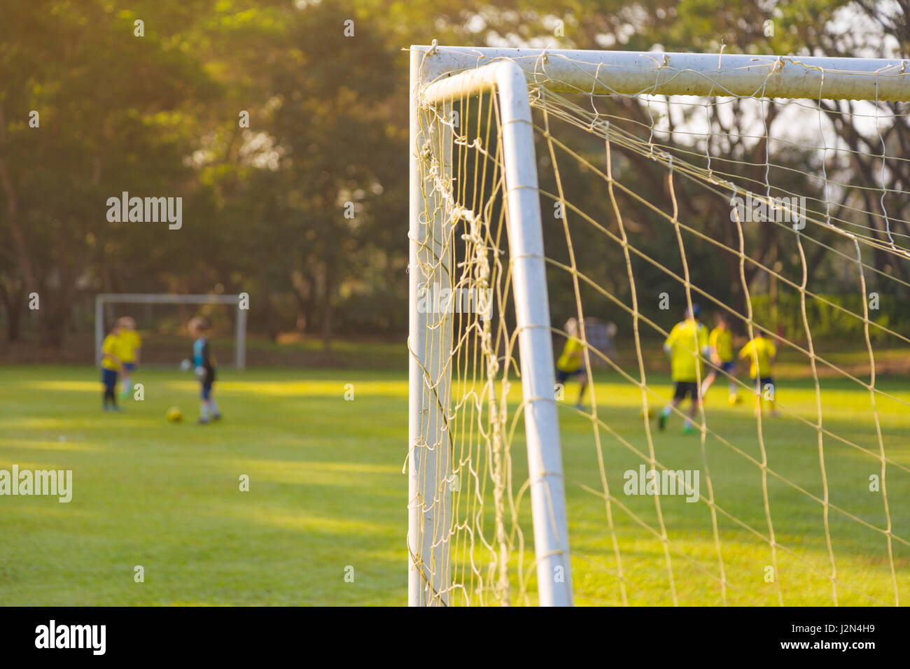 Ecke von einem Fußball oder Football Torpfosten mit warmen Morgenlicht und unscharfen Spielern und Bereich im Hintergrund Stockfoto