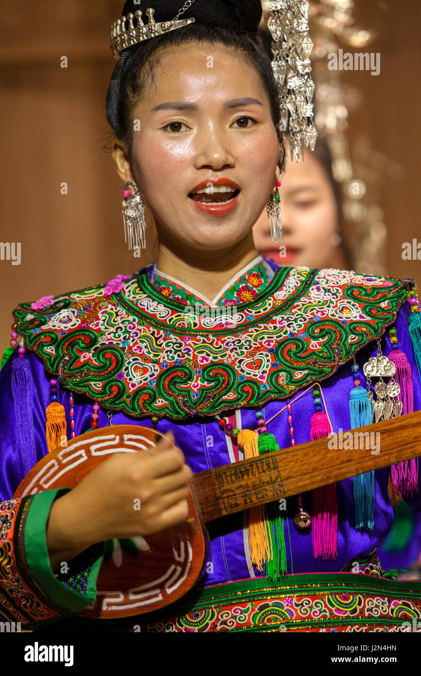 Zhaoxing, Guizhou, China.  Junge Frau der Dong ethnischen Minderheit spielen Pipa, eine fünf-saitige Laute. Stockfoto
