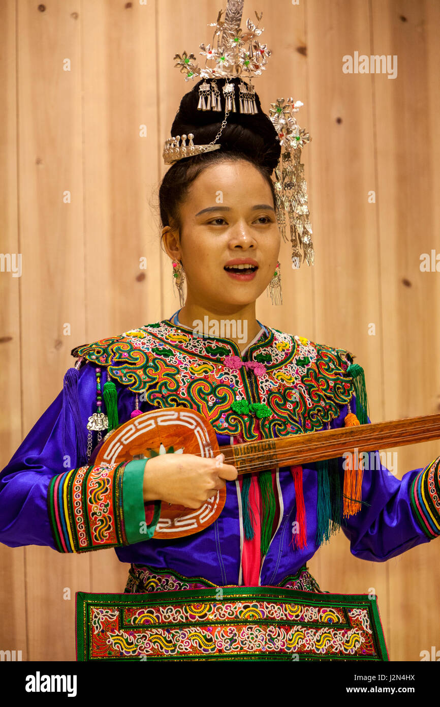 Zhaoxing, Guizhou, China.  Junge Frau der Dong ethnischen Minderheit spielen Pipa, eine fünf-saitige Laute. Stockfoto