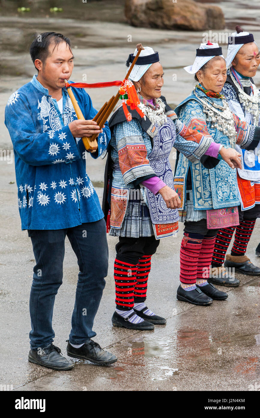 Matang, einem Gejia Dorf in Guizhou, China.  Frauen und Flötenspieler begrüßen die Besucher ins Dorf. Stockfoto