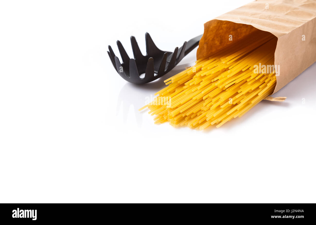 Rohe Spaghetti Nudeln Austreten von Braun von Papiertüte auf weißem Hintergrund mit Platz für Exemplar Stockfoto