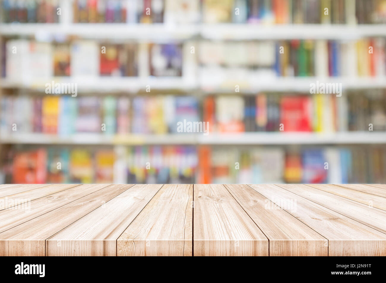 Leere hölzerne Tischplatte mit Unschärfe Bücherregale in Buchhandlung Hintergrund. kann sein Produkt Display verwendet. Stockfoto