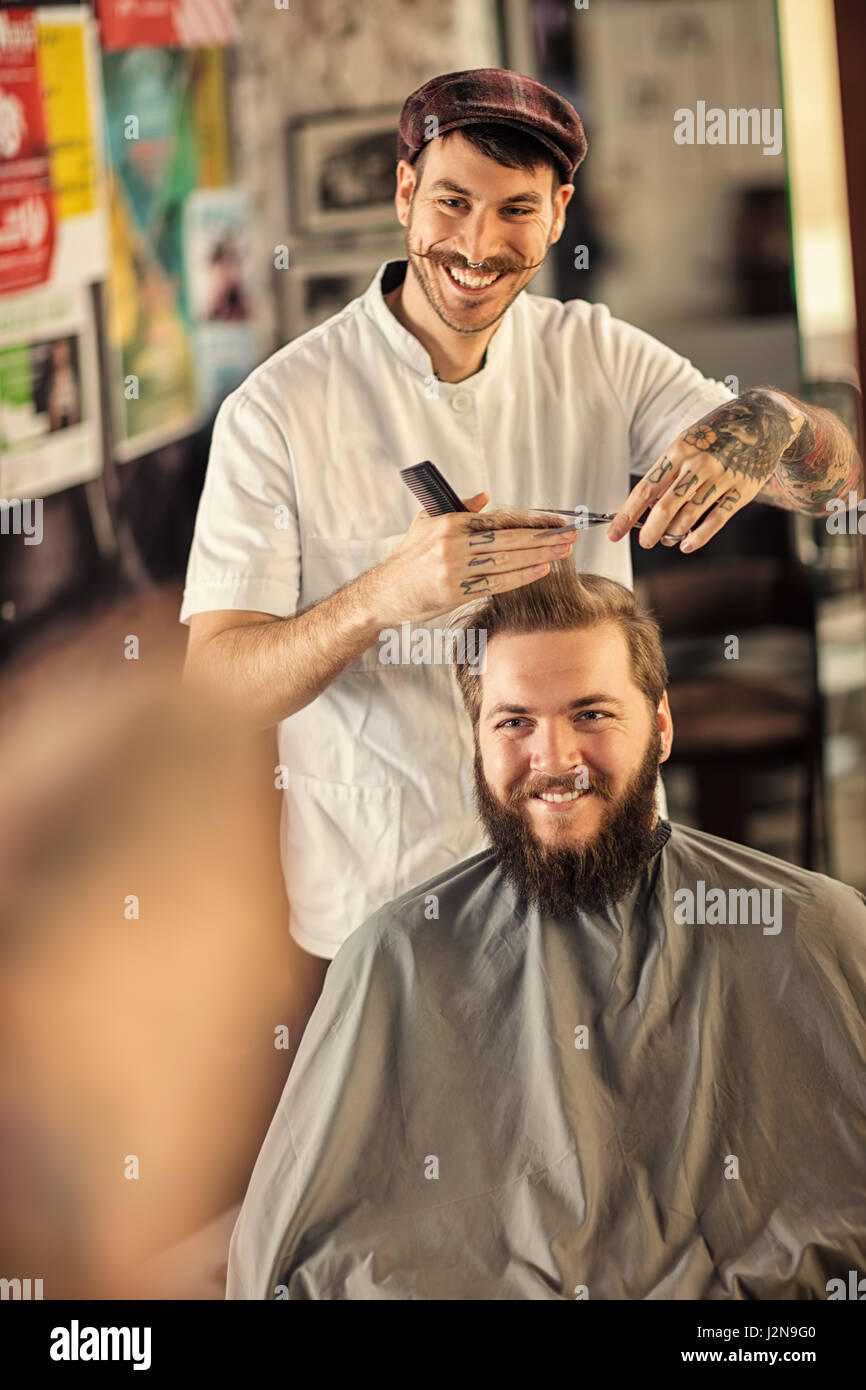 lächelnder Mann Friseur schneidet Haare des Clients Stockfoto