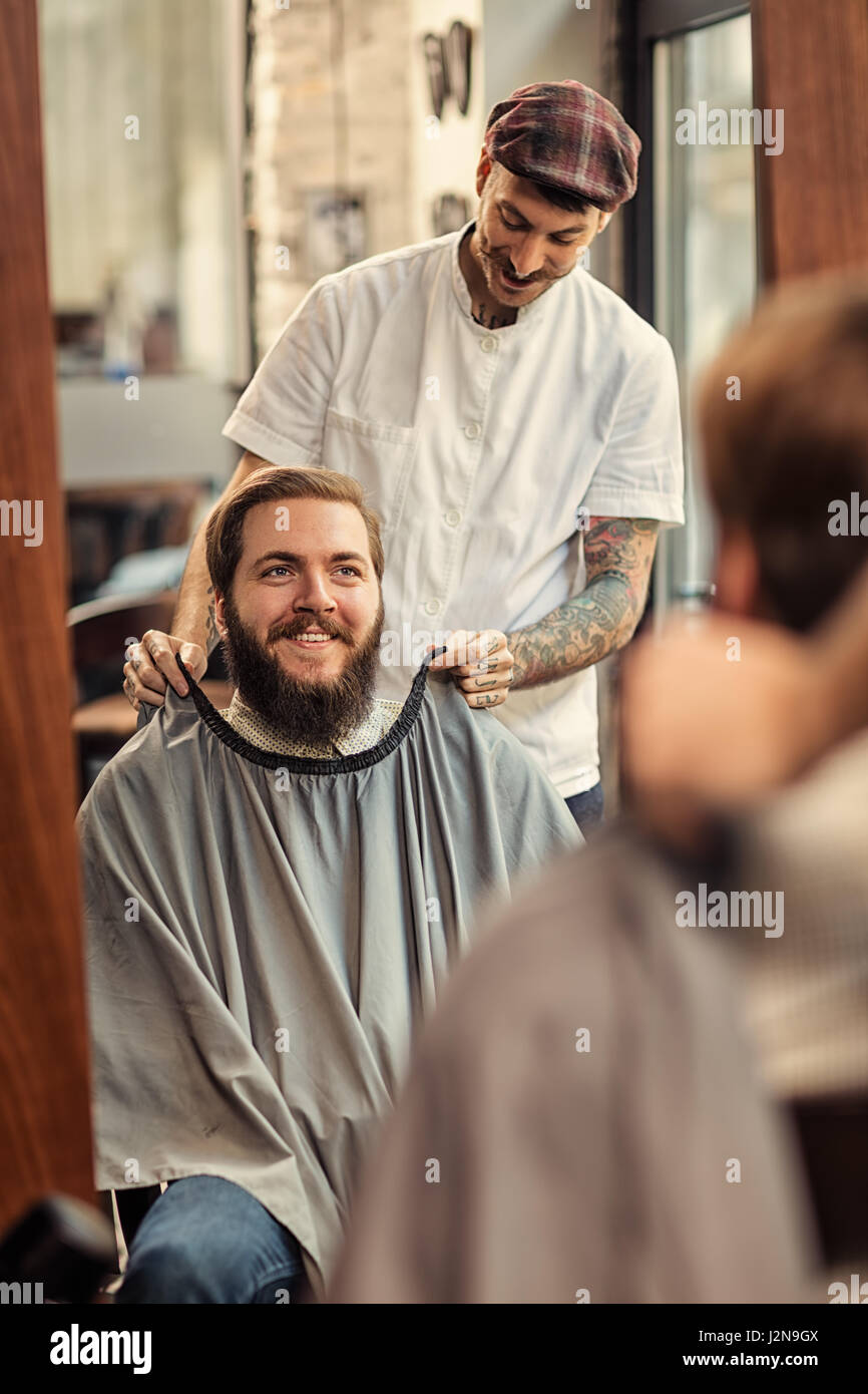 Hipster sitzt im Barber Shop Front der Spiegel Stockfoto