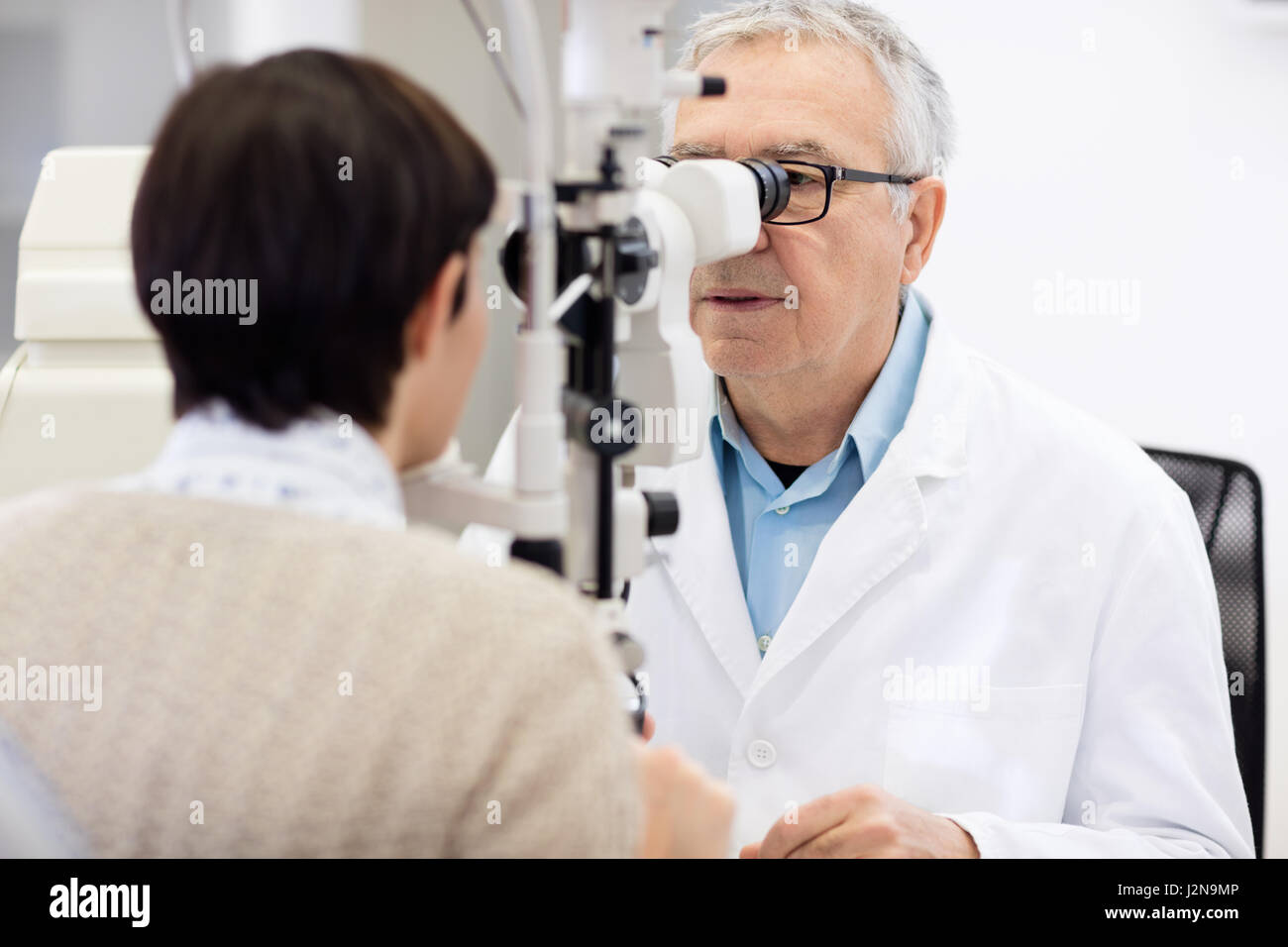 Ältere männliche Augenarzt in Ophthalmoskop schauen und Auge überprüfen Stockfoto