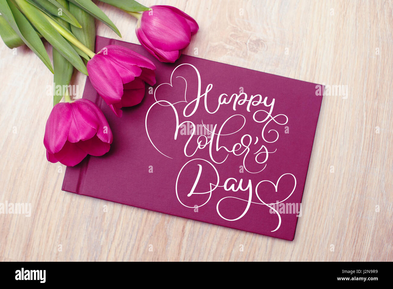 Drei violette Tulpen mit Karte und Text Happy Muttertag. Kalligraphie-Schriftzug Hand zeichnen Stockfoto