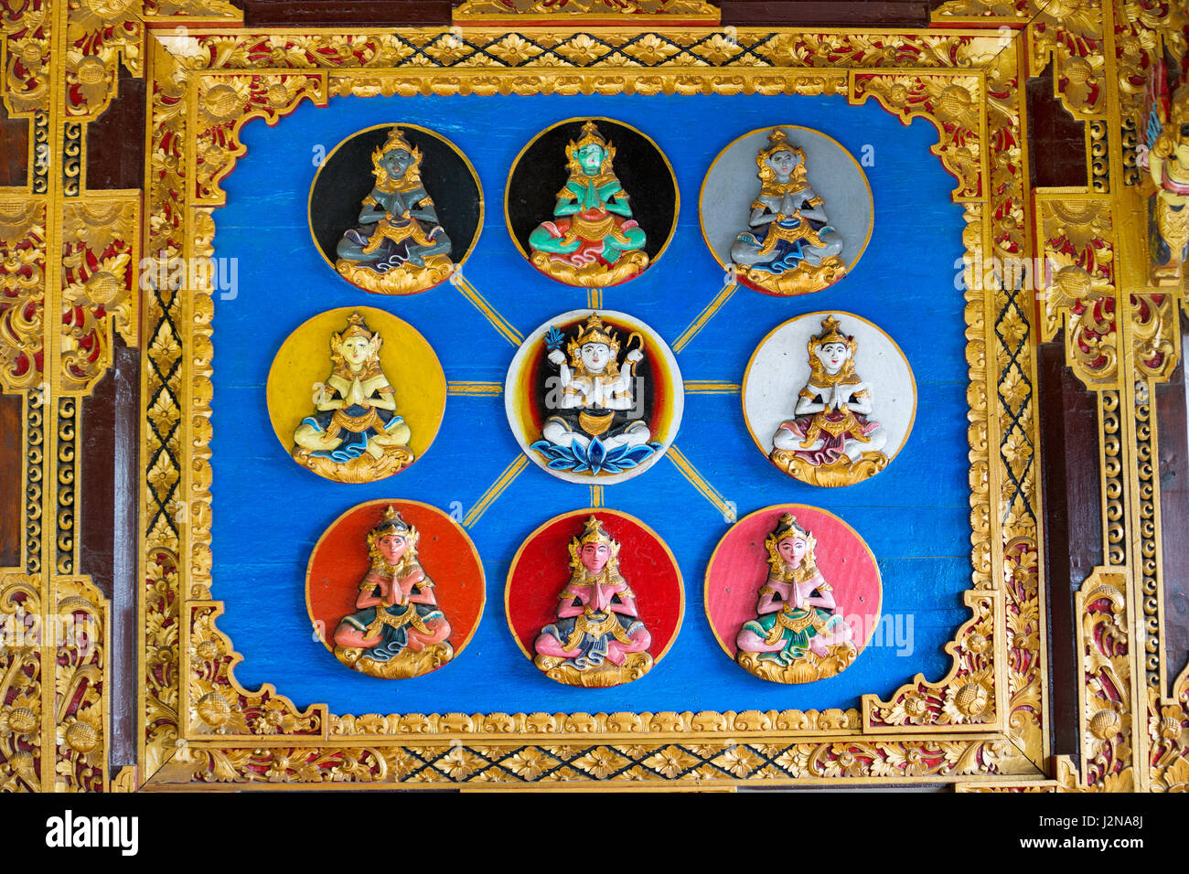 Traditionelle geschnitzte Holz Tür lackiert in den Farben in einem balinesischen Tempel, verziert mit floralen Ornamenten und Szenen aus der hinduistischen Mythologie mit Menschen Figur Stockfoto Traditionelle geschnitzte Holz Tür lackiert in den Farben in einem balinesischen Tempel, verziert mit floralen Ornamenten und Szenen aus der hinduistischen Mythologie mit Menschen Figur Stockfoto