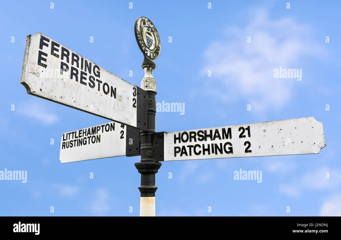Alten schmutzig typisch britische 3 Weise aus Holz Richtung Finger Post anmelden Angmering Village, West Sussex, England, UK. Stockfoto