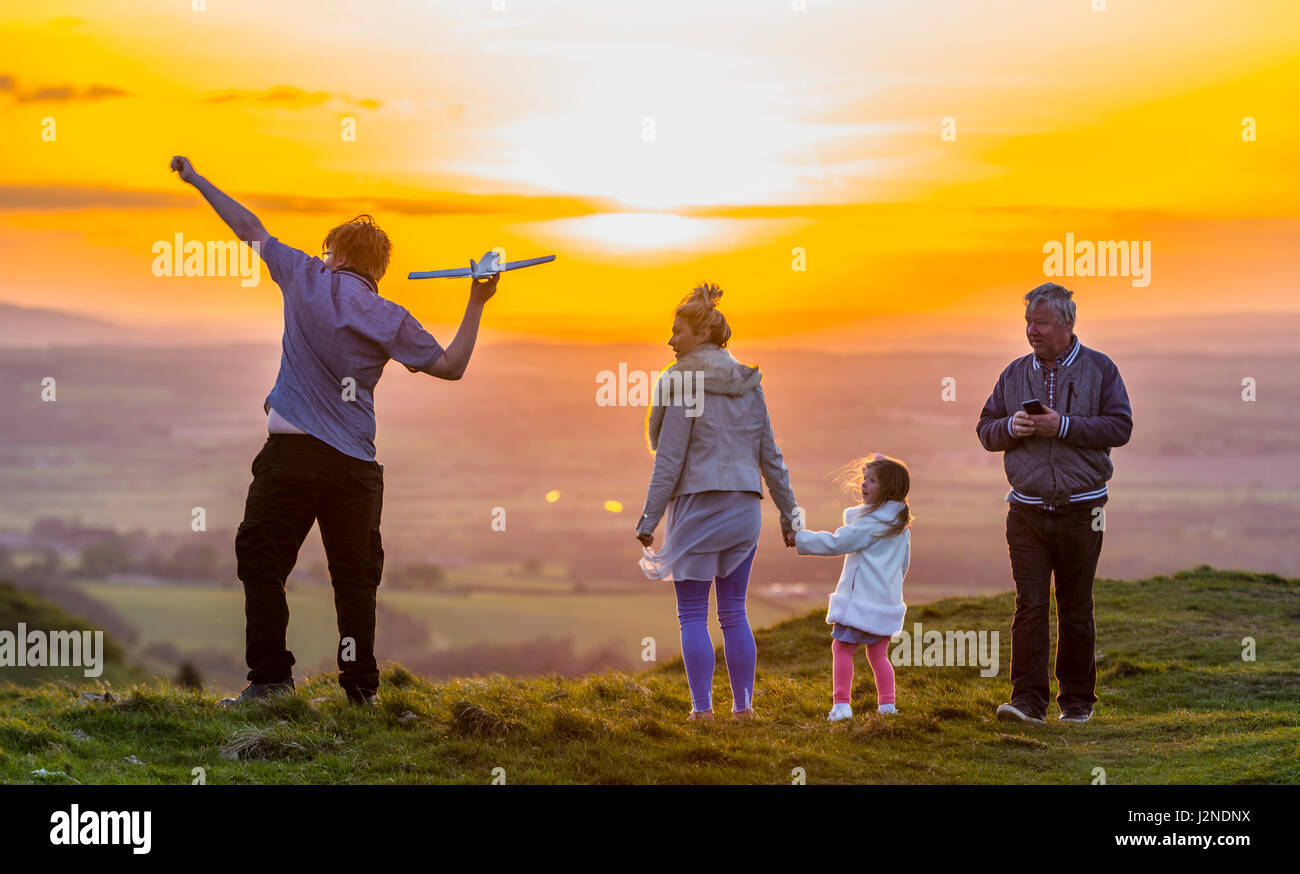 Liebevolle Familie spielen und gute Zeiten auf einem Hügel in der Nähe von Sonnenuntergang in der UK-Landschaft zu genießen. Zeit miteinander zu verbringen. Stockfoto
