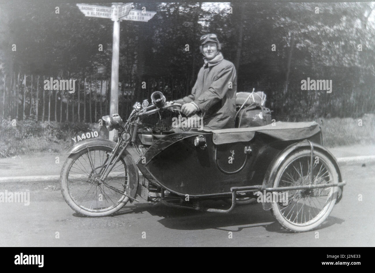 Frau reitet ein klassisches Douglas Motorrad und Beiwagen in England, trägt Brille und langen Mantel. Stockfoto