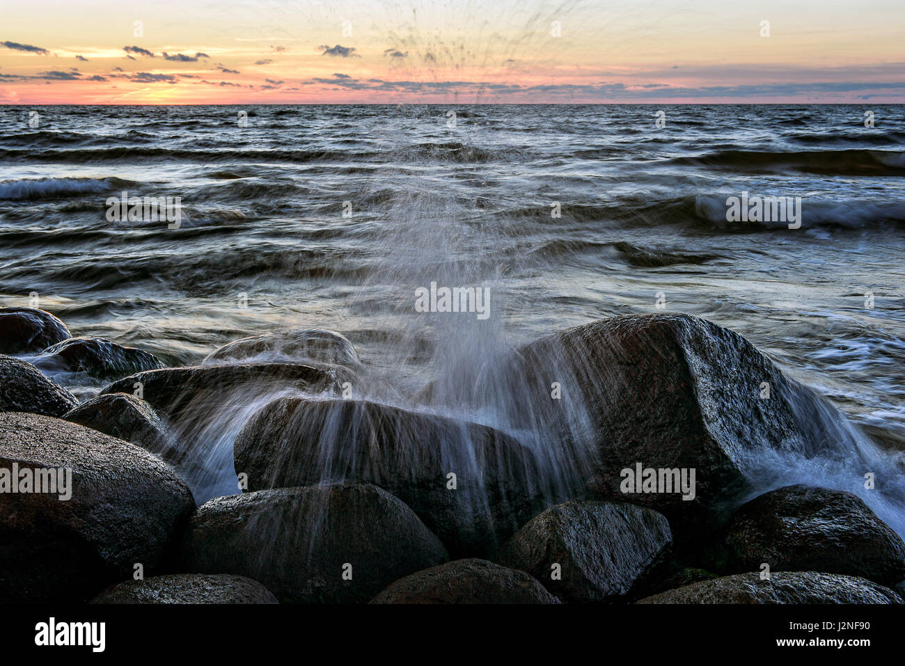 Die neunte Welle. Felsigen Ostseestrand bei Sonnenuntergang. Stockfoto