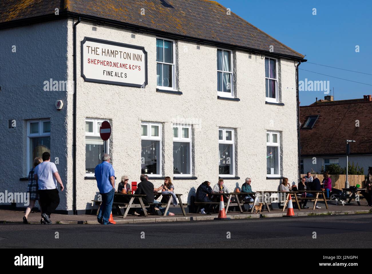 Herne Bay, Kent, UK. 29. April 2017. UK-Wetternachrichten.  Ein sonniger Abend am ersten Tag der Mayday Bank Holiday Wochenende ermöglicht es Menschen, die an den Strand zu gehen, obwohl sie gegen die Kälte verpackt bleiben und draußen das Hampton Inn einen Pub am Ufer sitzen. Bildnachweis: Richard Donovan/Live Alamy News Stockfoto