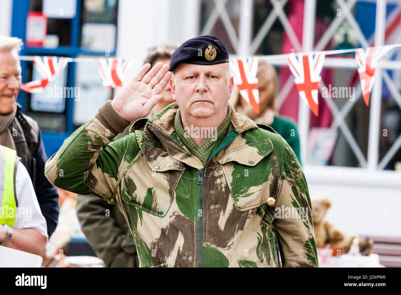 Gruß an die 40s Ereignis. Britische reife Offizier im battledress und Baskenmütze, mit sehr ernsten Ausdruck ständige Aufmerksamkeit salutierte während einer Minuten Stille. Stockfoto