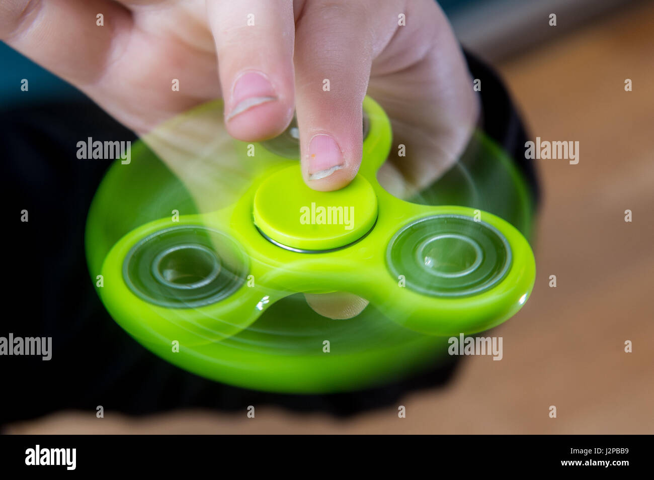 Ein kleiner Junge splays mit einem grünen Fidget spinner Stockfoto