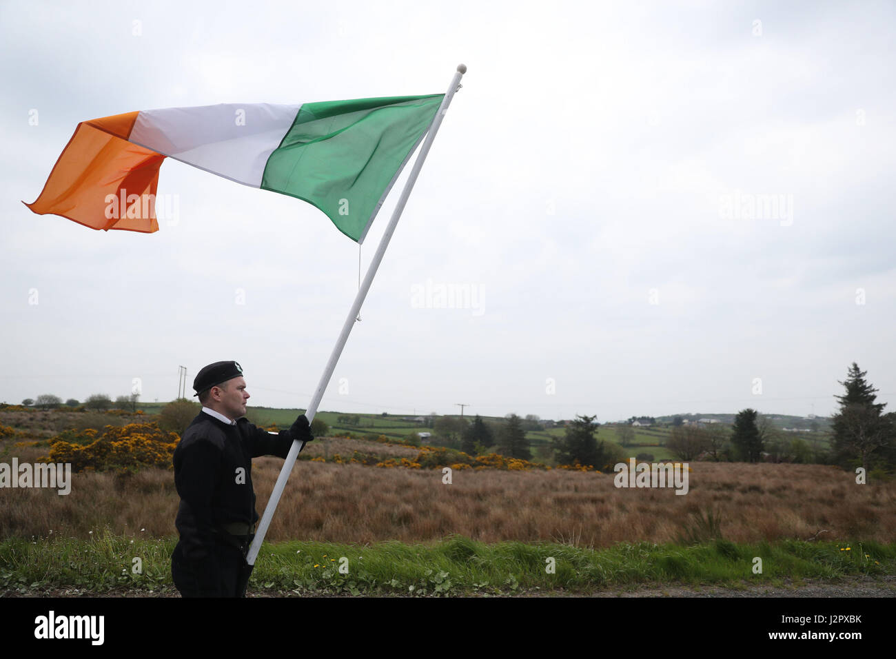 Ein Fahnenträger trägt die irische Trikolore während eines Marsches, Cappagh, Co Tyrone, anlässlich des 30. Jahrestages der schießenden Toten acht IRA-Mitglieder und Zuschauer Anthony Hughes in einem SAS-Hinterhalt in Loughgall, Co-Armagh. Stockfoto