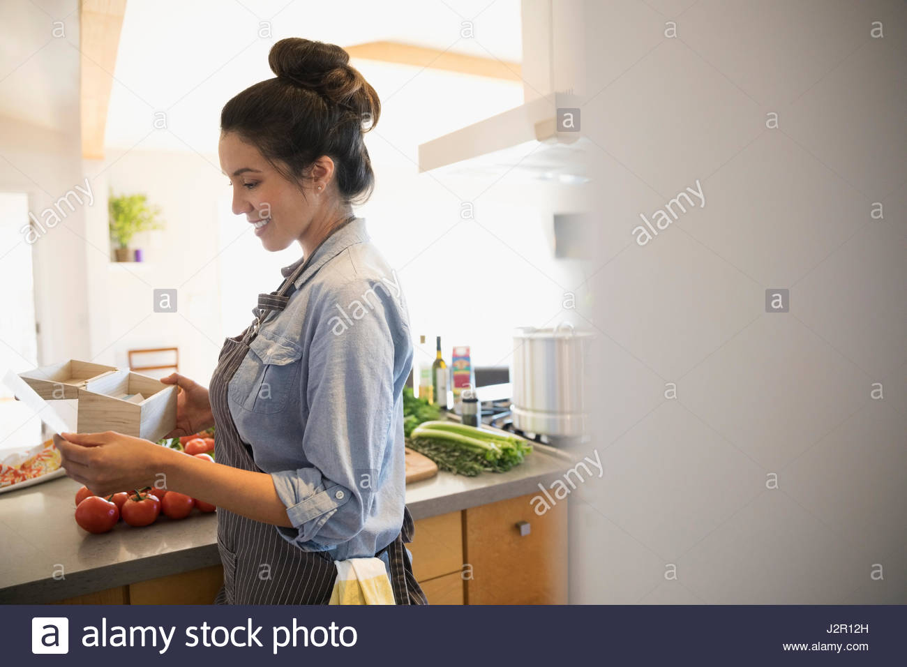 Lächelnde Latina-Frau mit Gemüse Rezept in Küche lesen Stockfoto