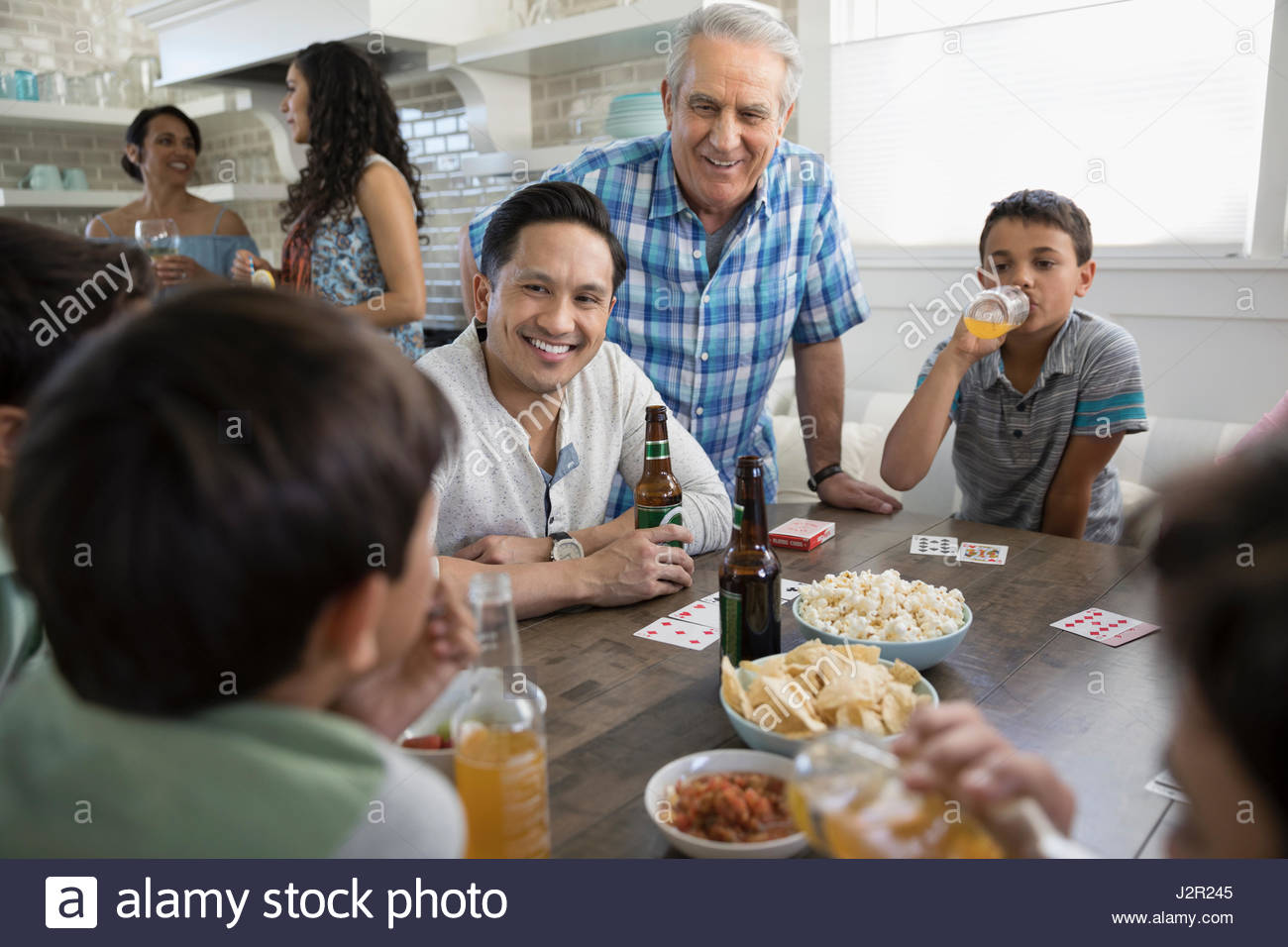 Generationsübergreifende Familie Spielkarten, Essen und trinken am Strand Haus Küchentisch Stockfoto