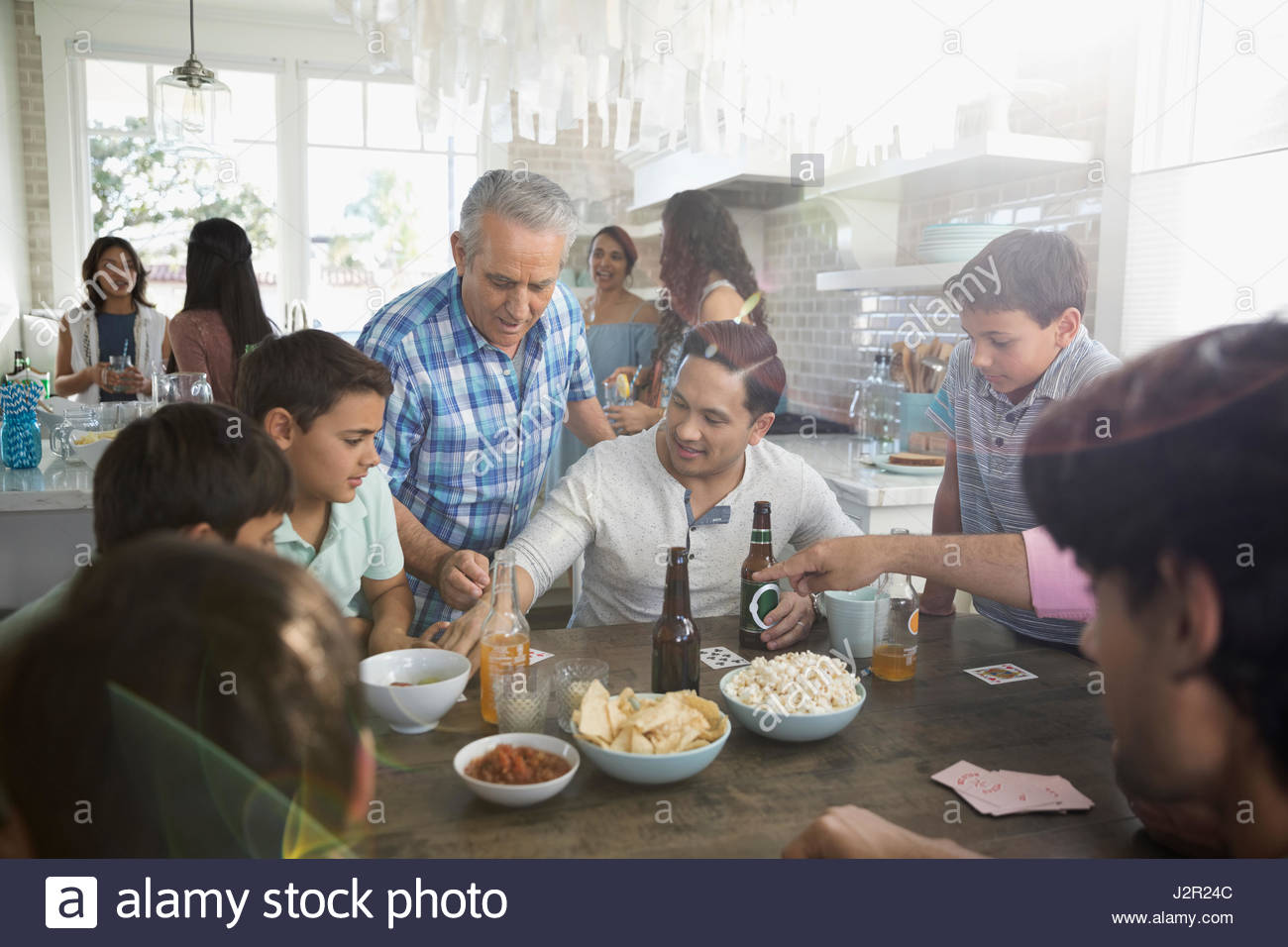 Generationsübergreifende Familie Spielkarten, Essen und trinken am Strand Haus Küchentisch Stockfoto