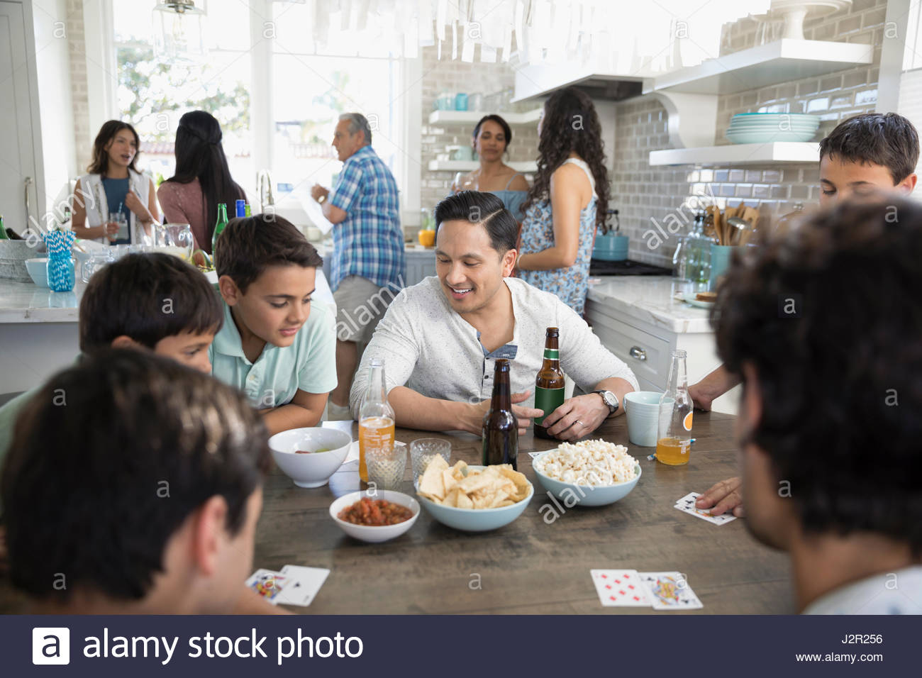 Vater und Söhne Spielkarten, Essen und trinken am Strand Haus Küchentisch Stockfoto