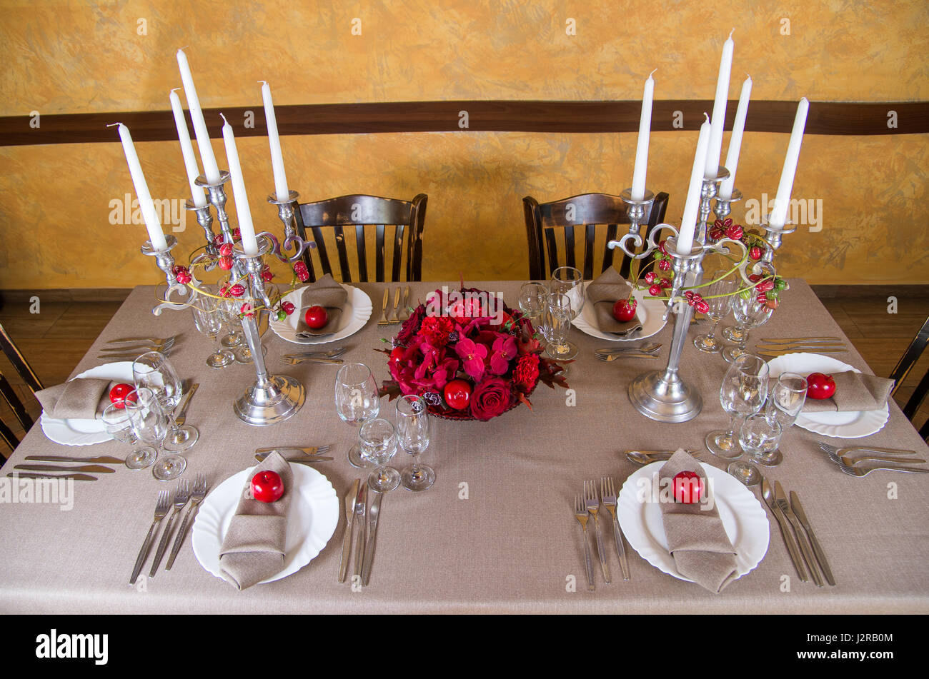 Festtafel dekoriert mit roten Blüten und Früchte Stockfoto