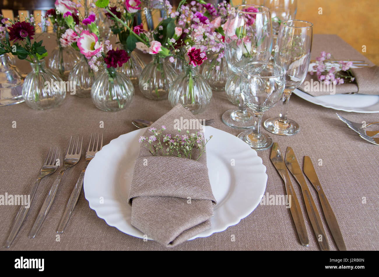 Tisch im Restaurant mit Besteck und Vasen mit Blumen Stockfoto