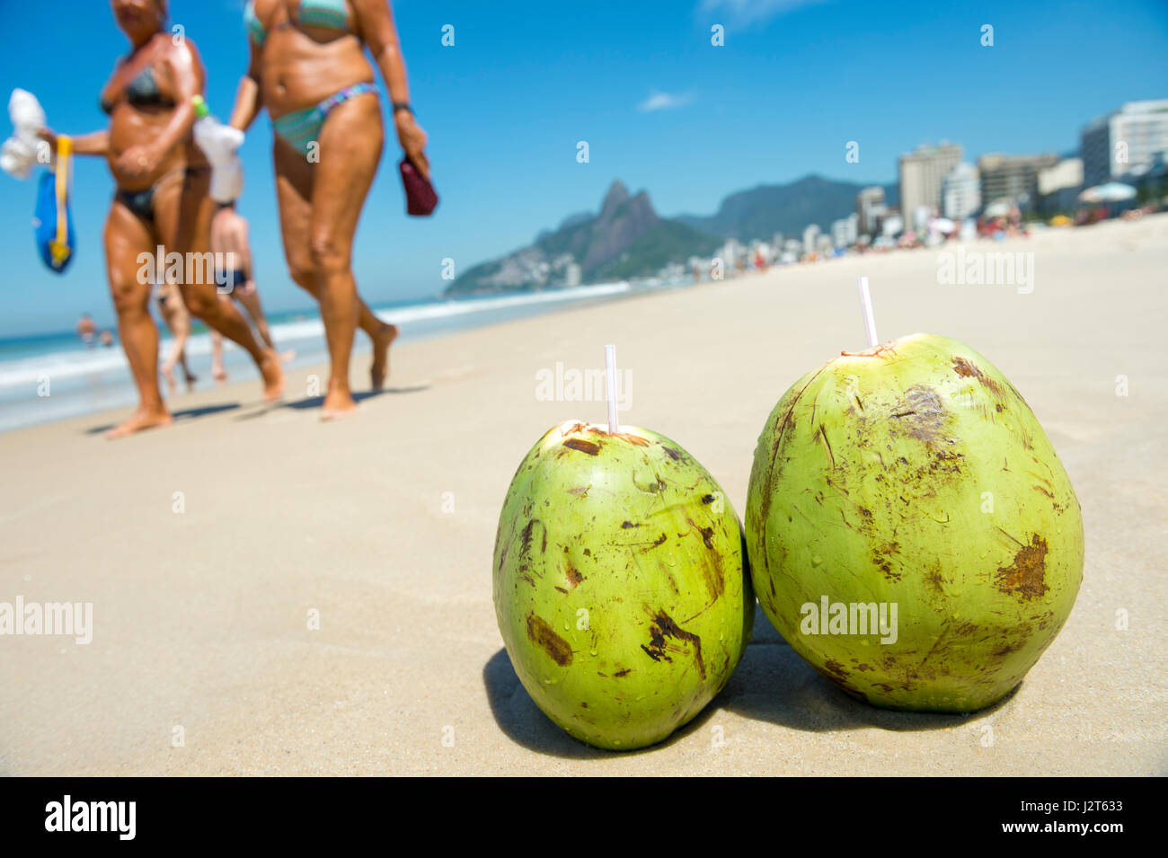 Paar von frischem Grün Kokosnüssen trinken am Ufer ausruhen, während Leute am Strand von Ipanema in Rio De Janeiro, Brasilien vorbeigehen Stockfoto