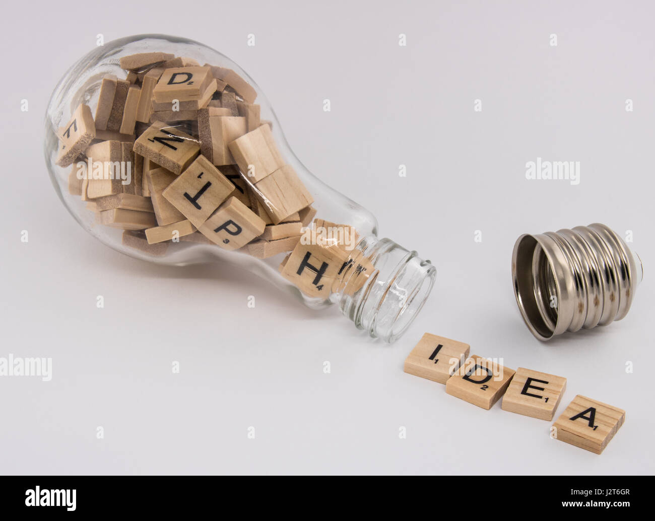 Eine Glühbirne mit einer abgeschraubt Socket gefüllt mit Buchstabensteine, spuckt das Wort "Idee" auf einem weißen Hintergrund. Stockfoto