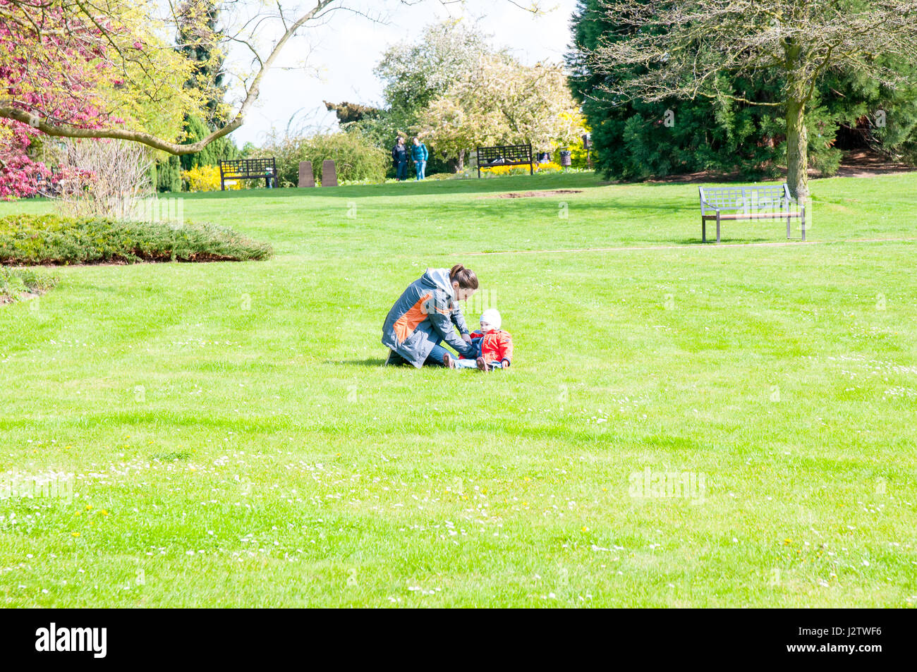 Mutter mit Kind, während er im Garten auf Rasen Stockfoto