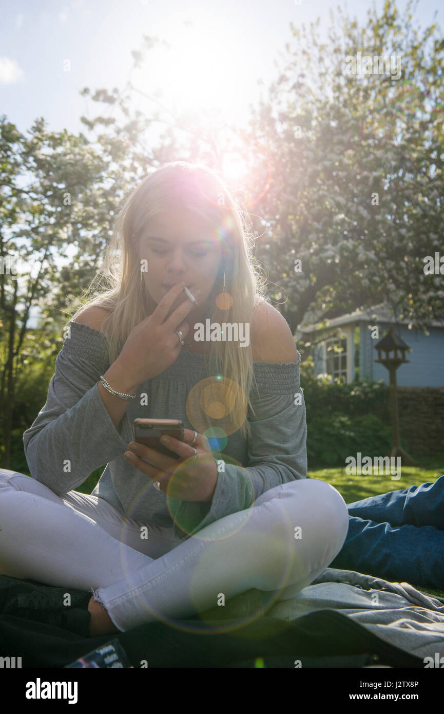 Eine junges Mädchen genießt eine Zigarette in der Sommersonne Stockfoto