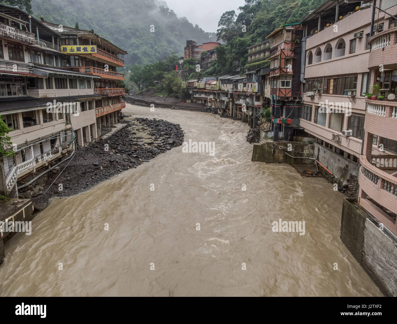 Wulai, Taiwan - 9. Oktober 2016: Landschaft von Gebäuden auf einem nebligen, regnerischen und üppigen Hügel an einem Fluss in Wulai Stockfoto
