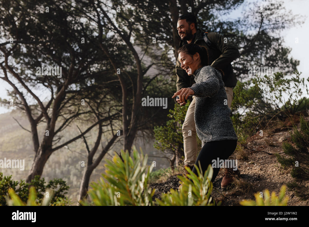 Glückliche junge Paare, die Spaß auf ihrer Wanderung, der Bergweg hinunter. Wanderer-paar amüsieren sich im Urlaub. Stockfoto