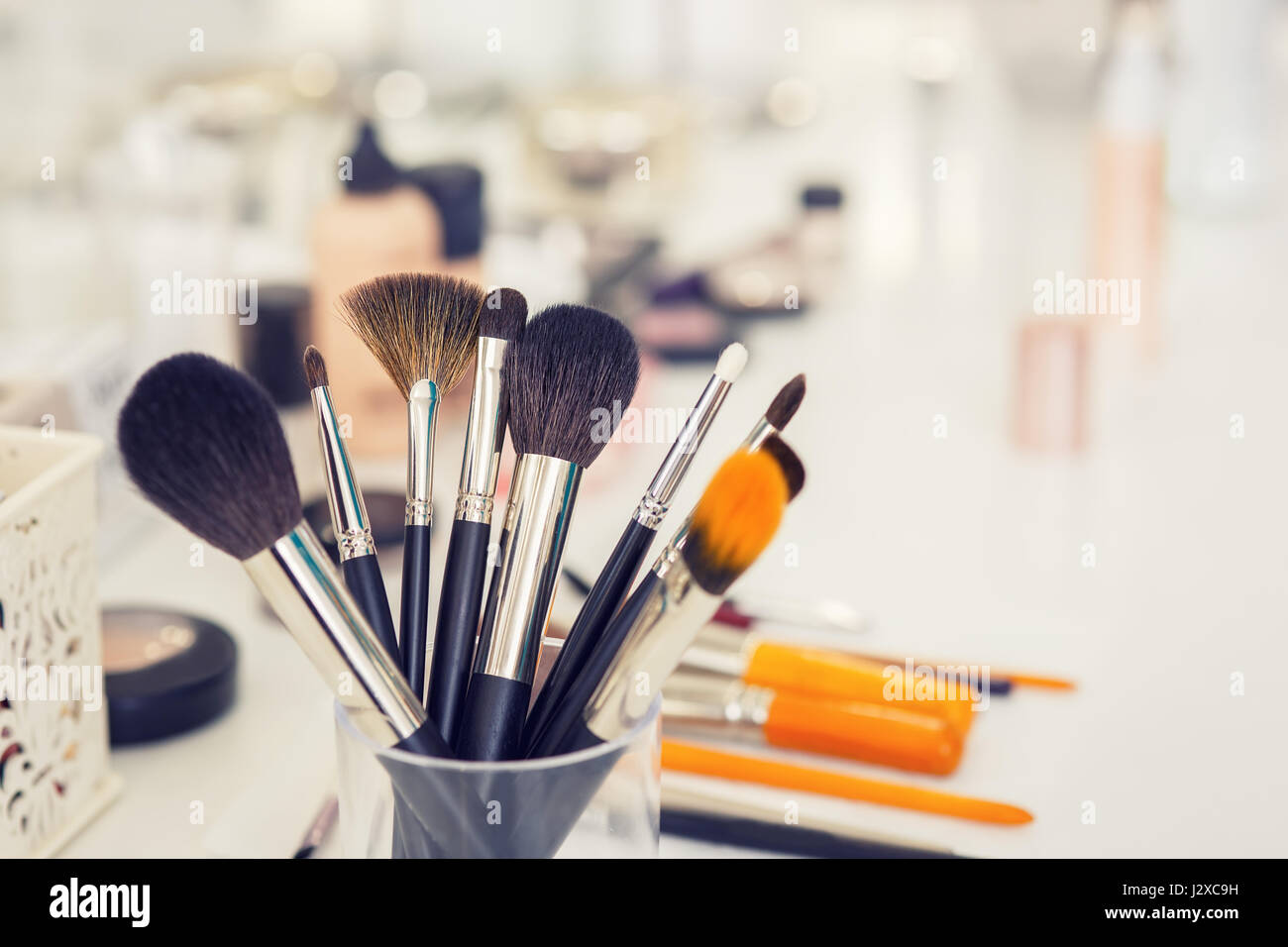 Satz von professionellen Make-up Pinsel in Glas am Tisch Closeup. Gefilterte Foto mit Tiefenschärfe und Muskelaufbau. Schminktisch im Beauty-Salon. Noch lif Stockfoto