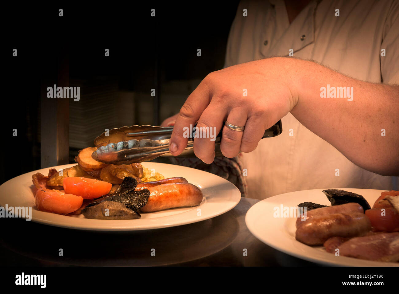 Restaurant Koch Lebensmittelzubereitung Full English Breakfast Fry gekochtes Frühstück Küche gegrillt Fried ungesunde britische Mahlzeit am Morgen essen Stockfoto