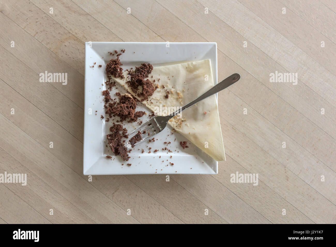 Speisereste ein Schokoladenkuchen Krümel Teller Gabel Besteck Serviette Serviette gegessen verbraucht zufrieden Zufriedenheit behandeln Genuss Stockfoto