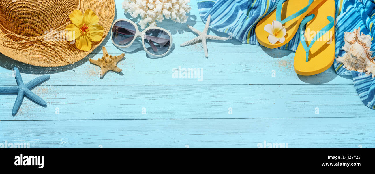 Strohhut, Handtuch, Sonnenbrille und Flip Flops auf blauem Hintergrund aus Holz Stockfoto