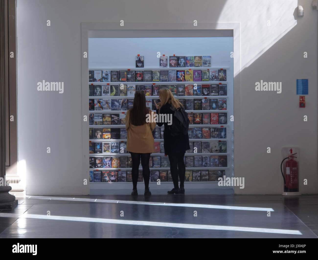 Zwei Mädchen, die Auswahl von DVDs in Glasgow GOMA Stockfoto