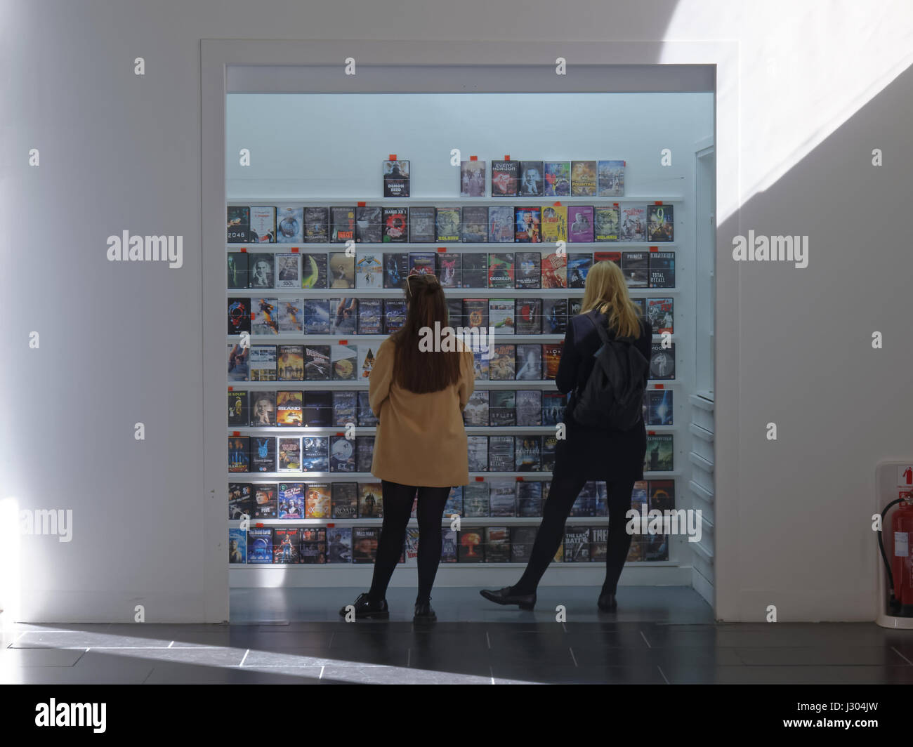 Zwei Mädchen, die Auswahl von DVDs in Glasgow GOMA Stockfoto