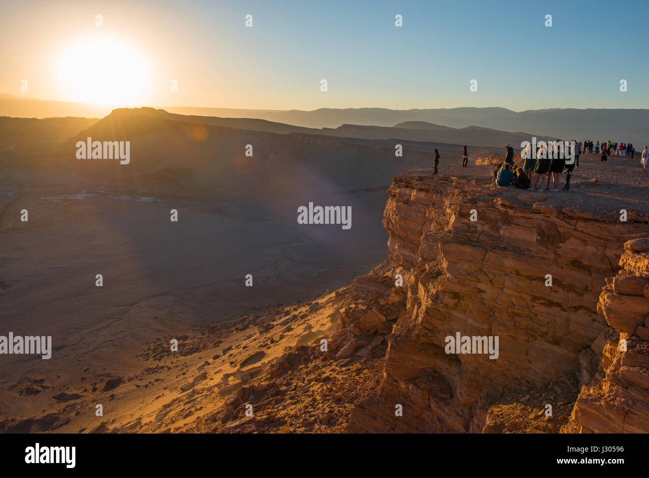 Touristen und Rucksacktouristen den Sonnenuntergang von einer Klippe über der Atacama-Wüste in der Nähe von San Pedro de Atacama im Norden von Chile. Stockfoto
