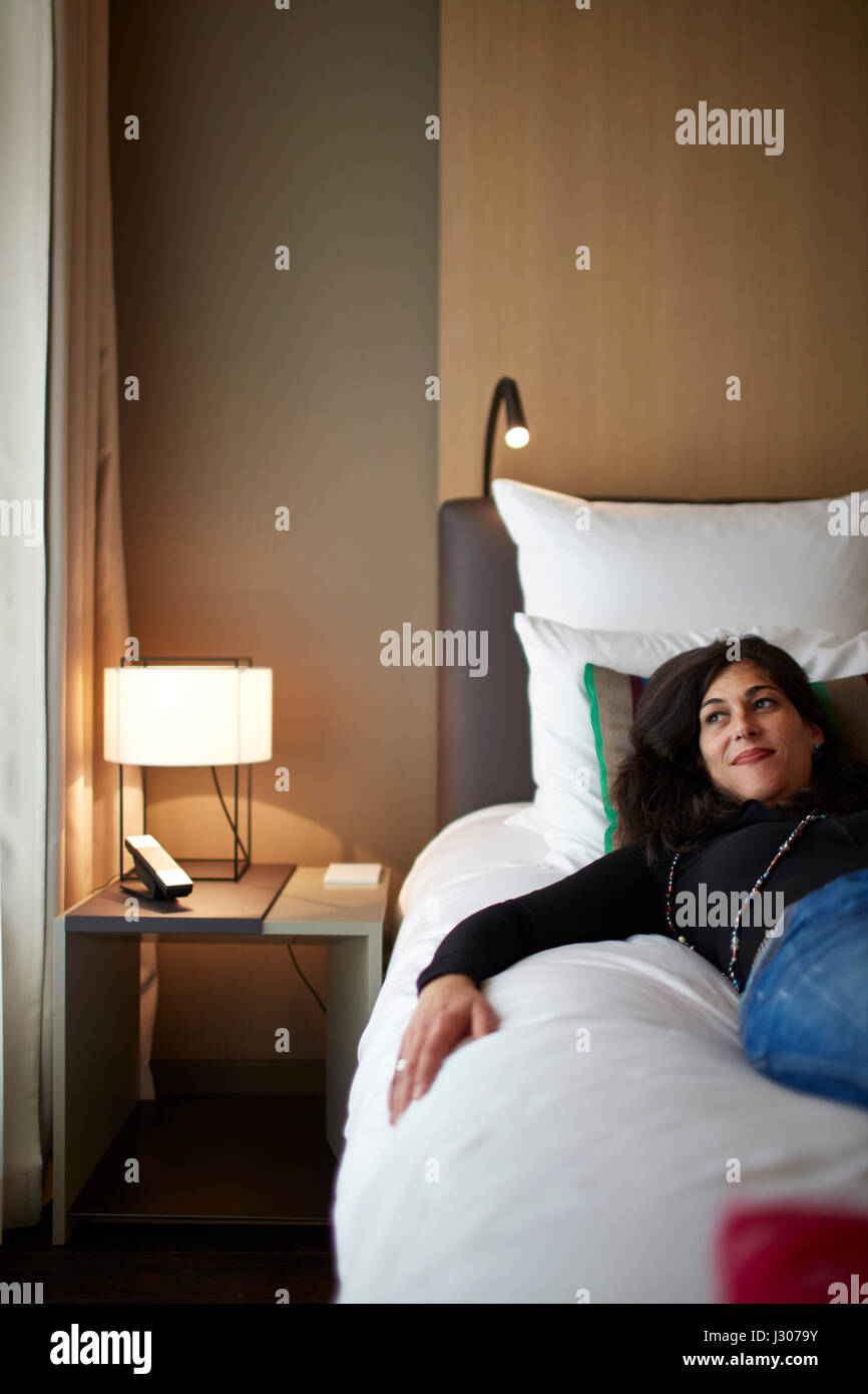 Frau liegend auf dem Bett in einem Standardzimmer, Das Stue Hotel, Drakestrasse 1, Tiergarten, Berlin, Deutschland Stockfoto