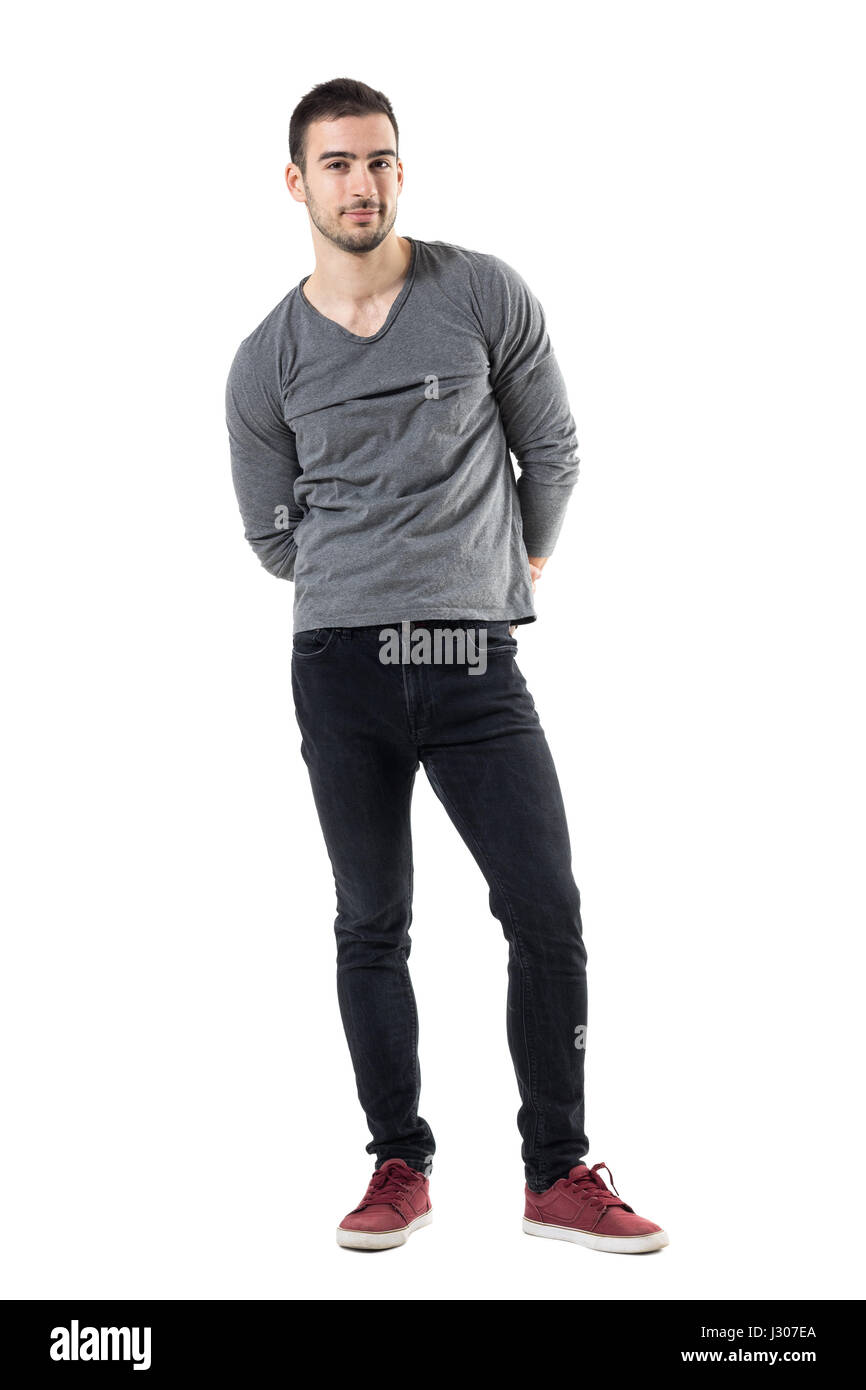 Junge hübsche legerer Mann mit Händen hinter zurück in die Kamera Lächeln. Ganzkörper-Länge-Porträt über weiße Studio-Hintergrund isoliert. Stockfoto