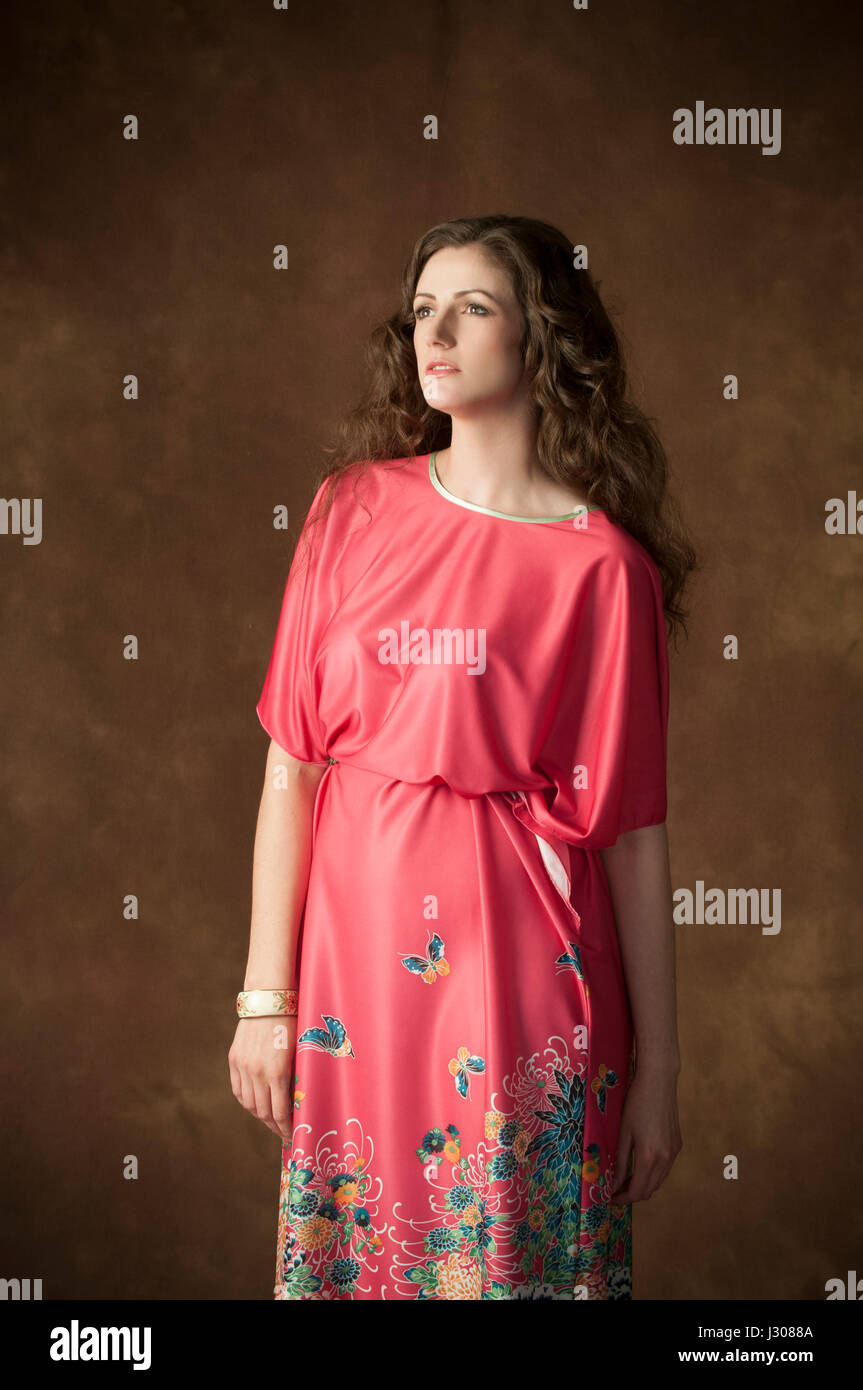 Schöne junge Frau trägt ein rotes Kleid Loooking entfernt Stockfoto